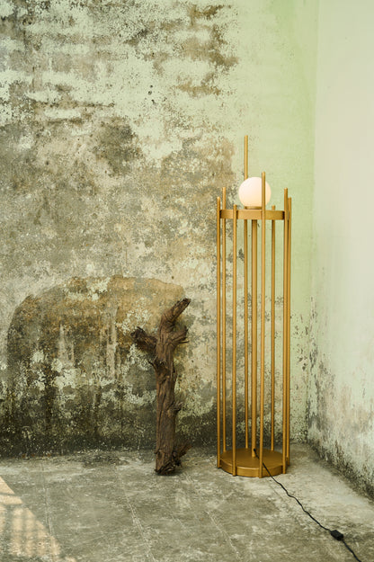 Gold decorative stand with a candle against a textured wall.