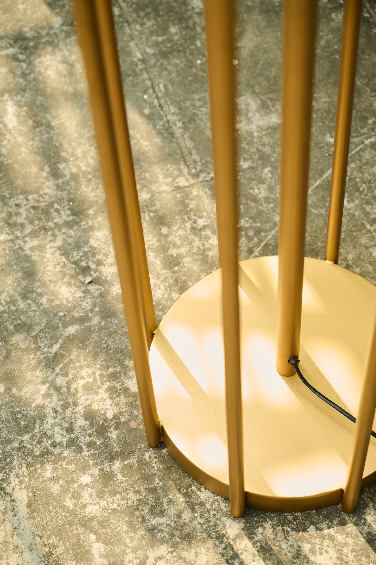 Gold floor lamp on a textured gray surface