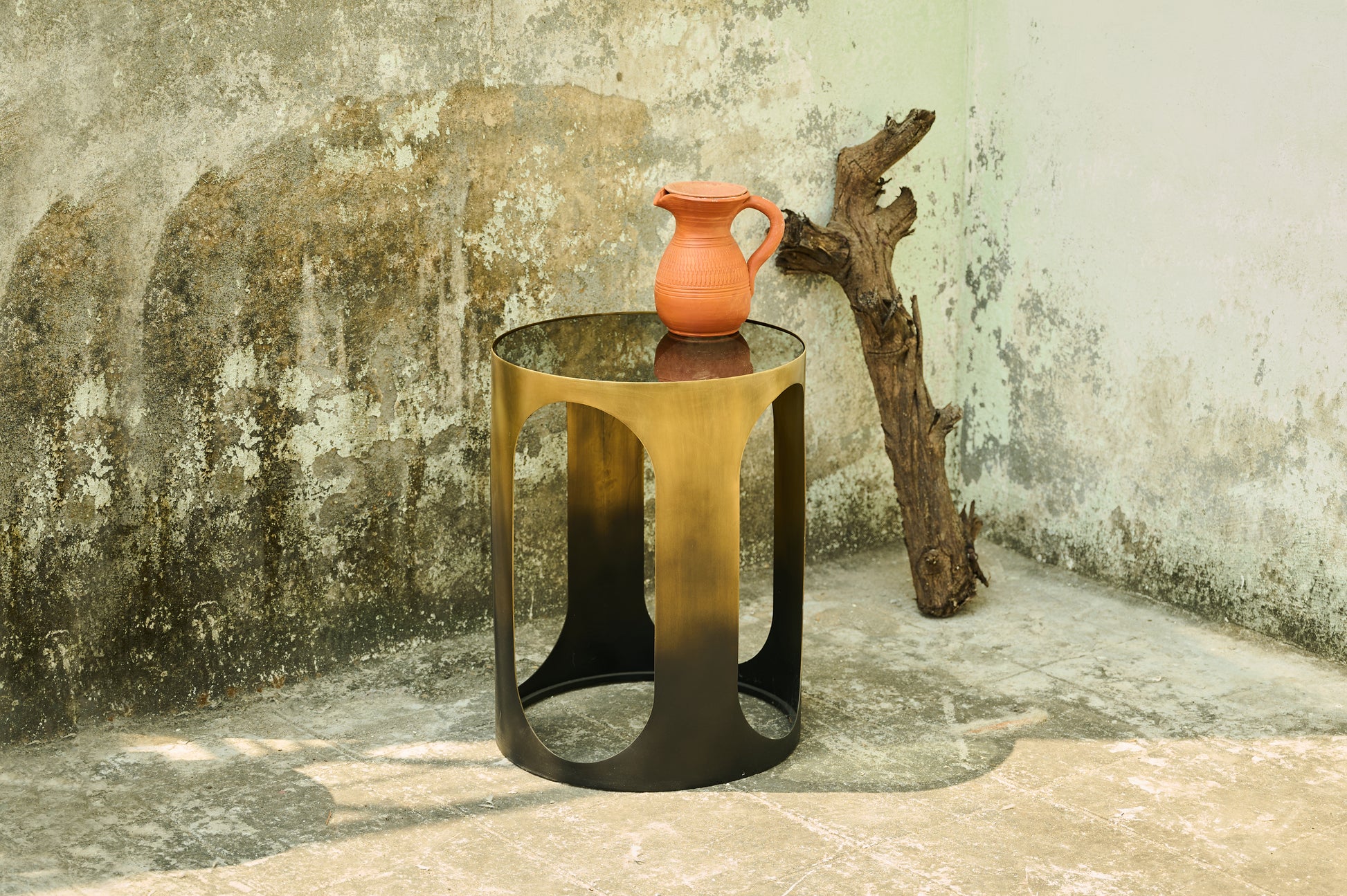 Small round table with a vase on it against a textured wall.