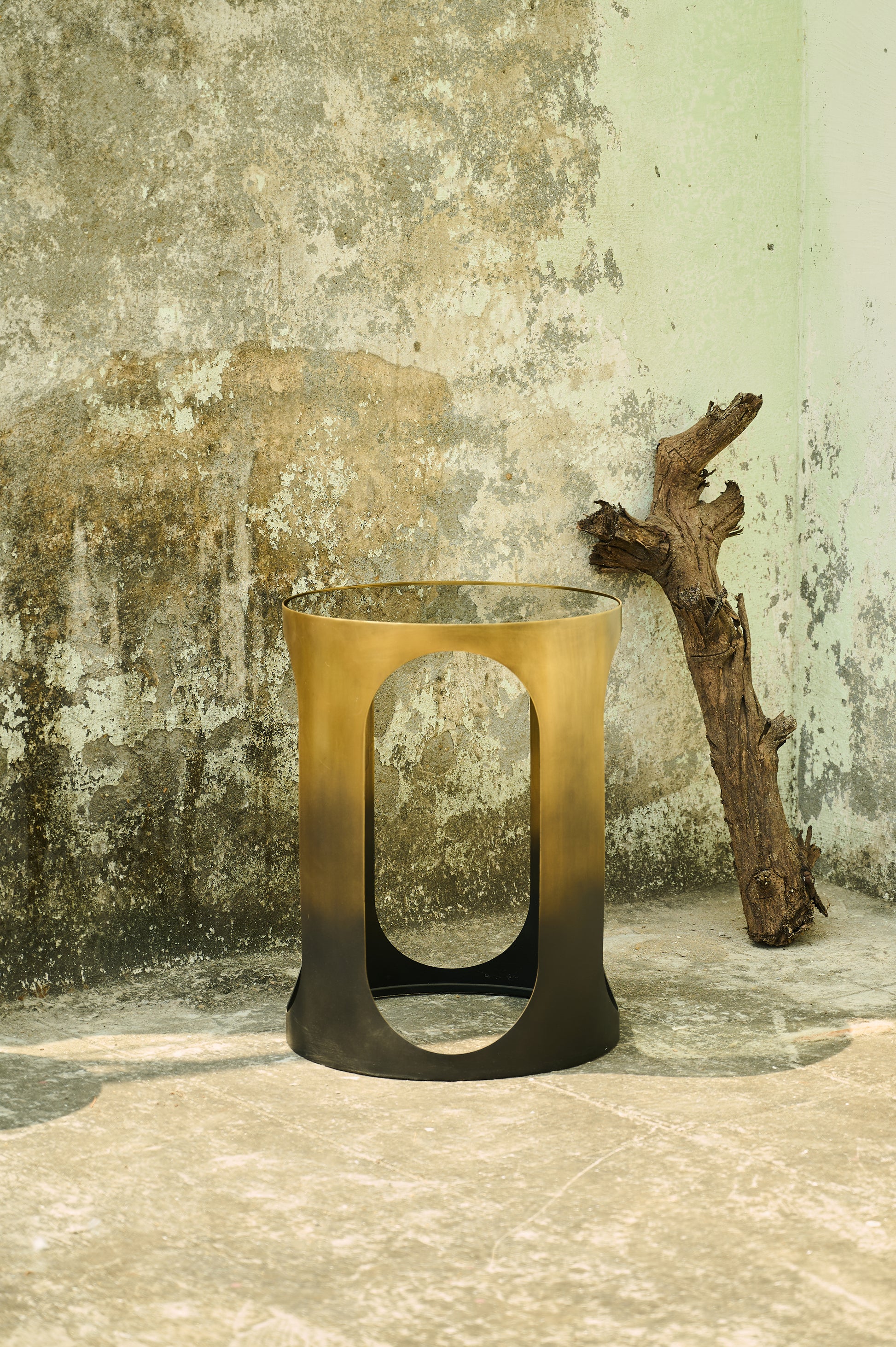 Bronze candle holder against a textured wall with a branch