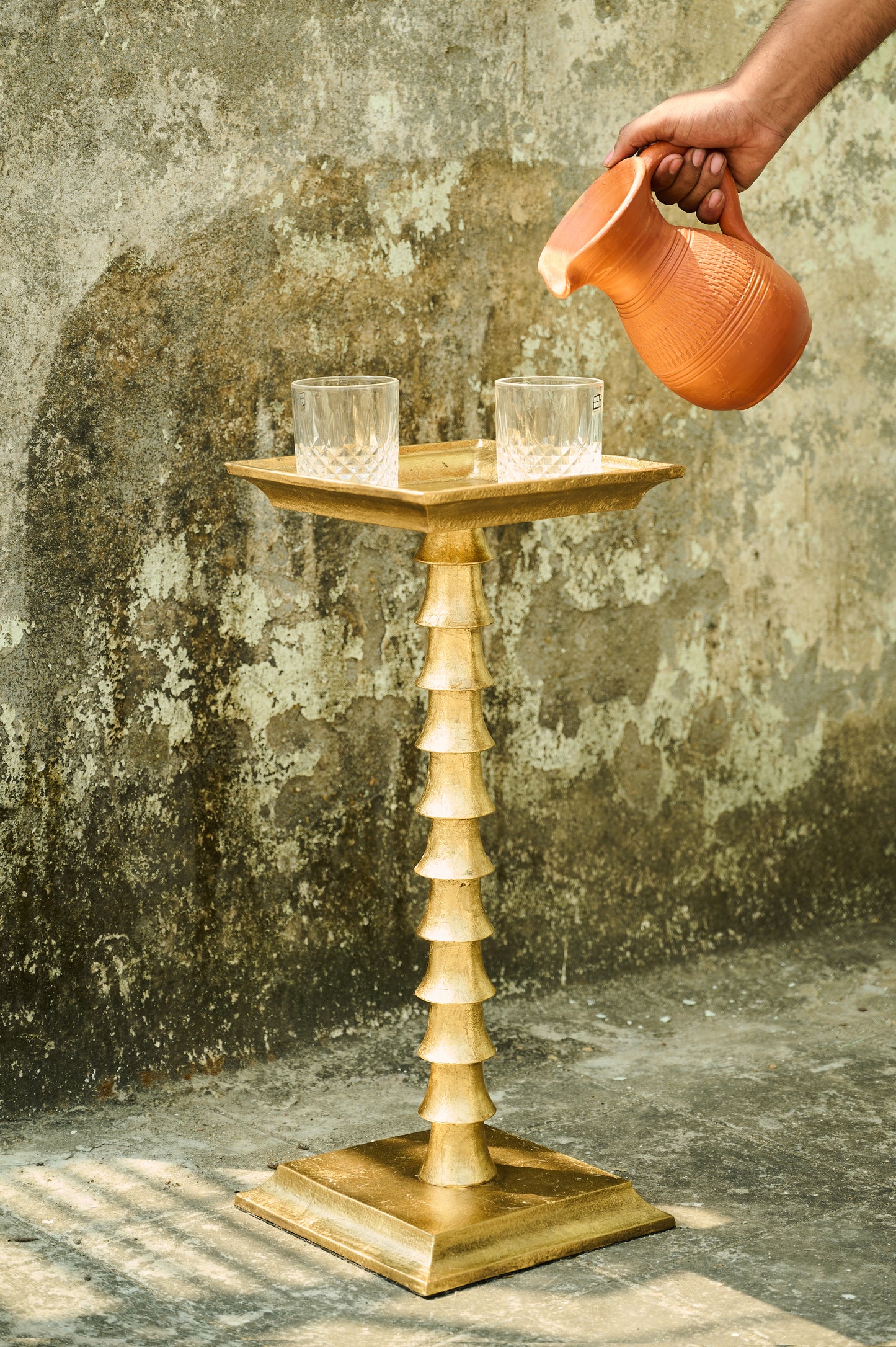 Wooden candle holder with two candles against a textured wall.