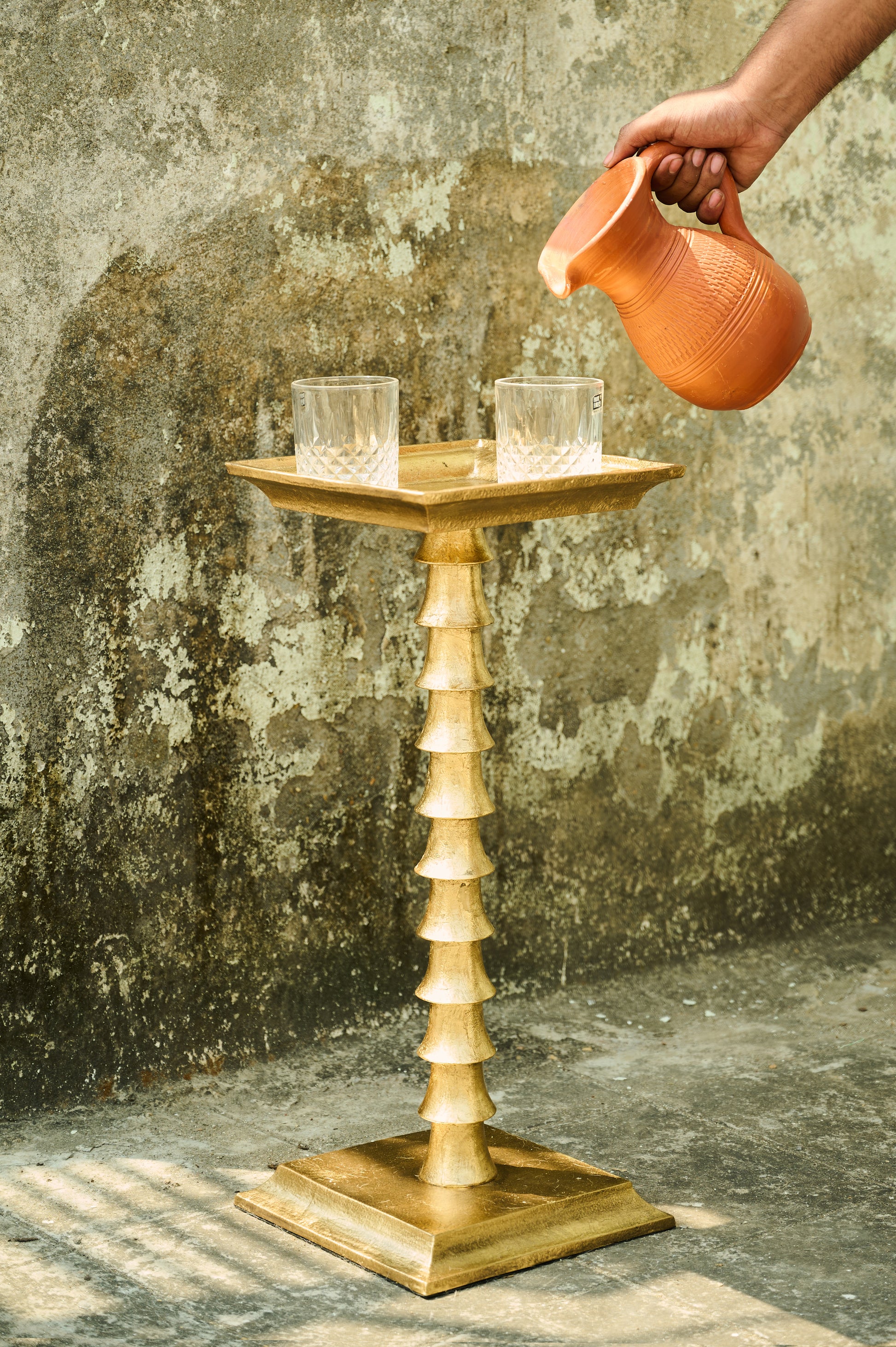 Wooden candle holder with two candles against a textured wall.